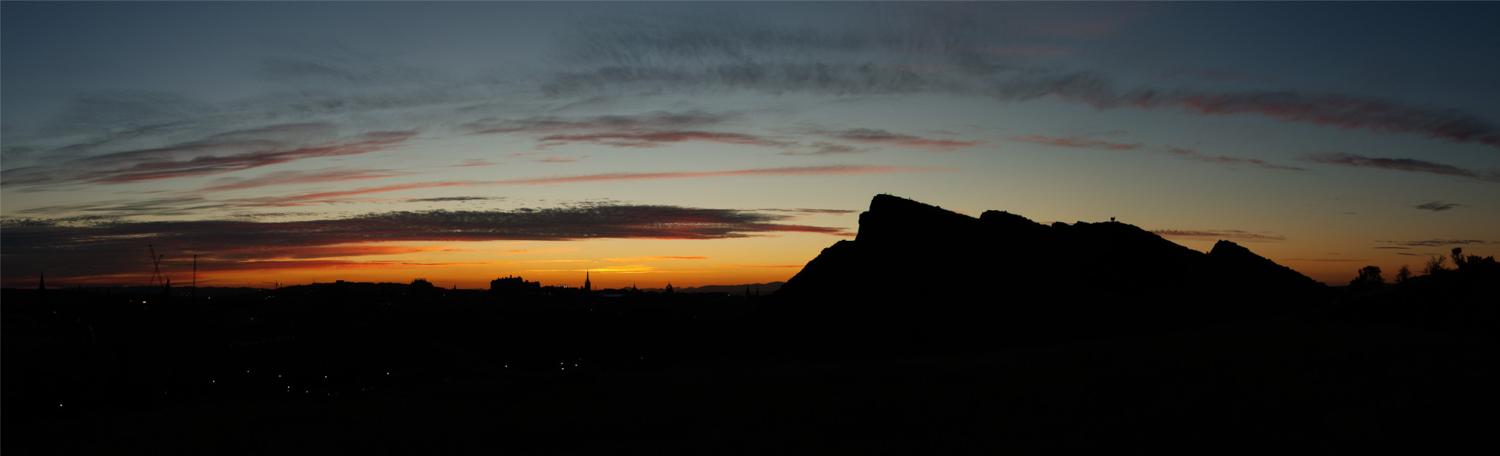 The summer sun setting behind Edinburgh Castle seen from the Magic Corner in Holyrood Park.